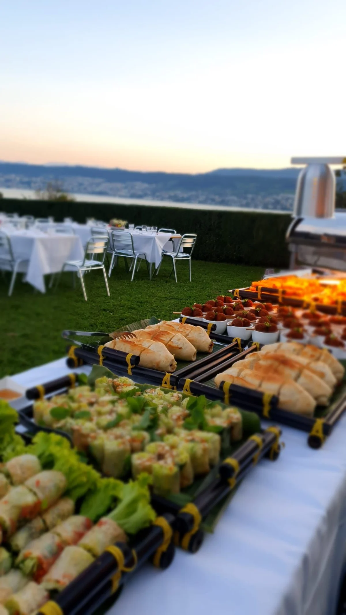 Sommerrollen und Fingerfood auf Catering-Buffet mit Seeblick bei Sonnenuntergang